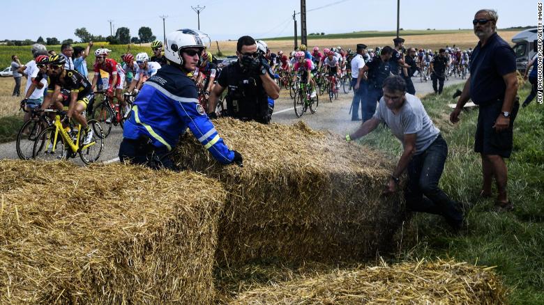Gendarmes remove haystacks that were placed on the stage&#39;s route.