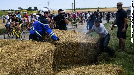 Gendarmes remove haystacks that were placed on the stage&#39;s route.