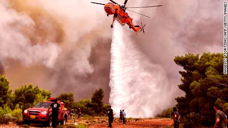 A firefighting helicopter drops water to extinguish flames Tuesday in the village of Kineta.