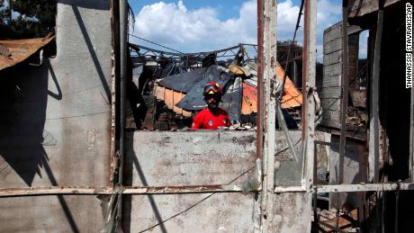 A member of a rescue team searches a burned house Wednesday in Mati.