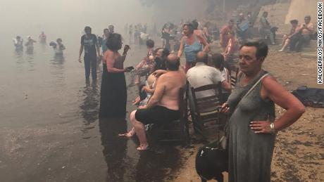 People take refuge Monday from the fires along the beach north of Mati.