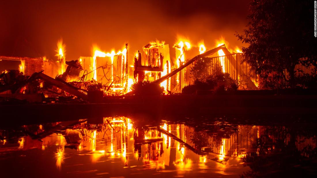 A burning home is reflected in a pool in Redding on July 27.