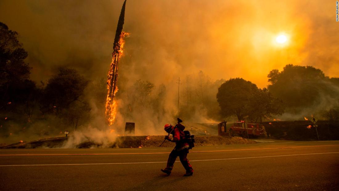 A firefighter walks along Highway 299 as the Carr Fire tears through Shasta on July 26.