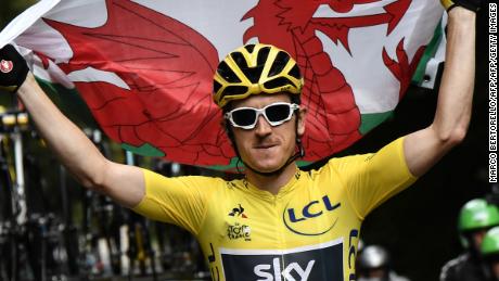 Geraint Thomas proudly holds the Welsh flag as he rides to victory on the final stage of the 105th Tour de France. 