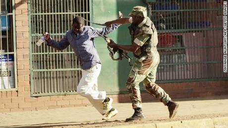 A Zimbabwean soldier beats a man in a street of Harare on Wednesday, August 1.