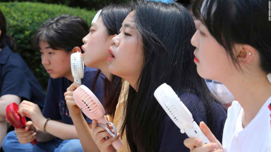 People use portable fans to cool down during a rally in Seoul, South Korea, on Wednesday, August 1. It was the hottest day in Seoul in 111 years, according to the Korean Meteorological Administration.