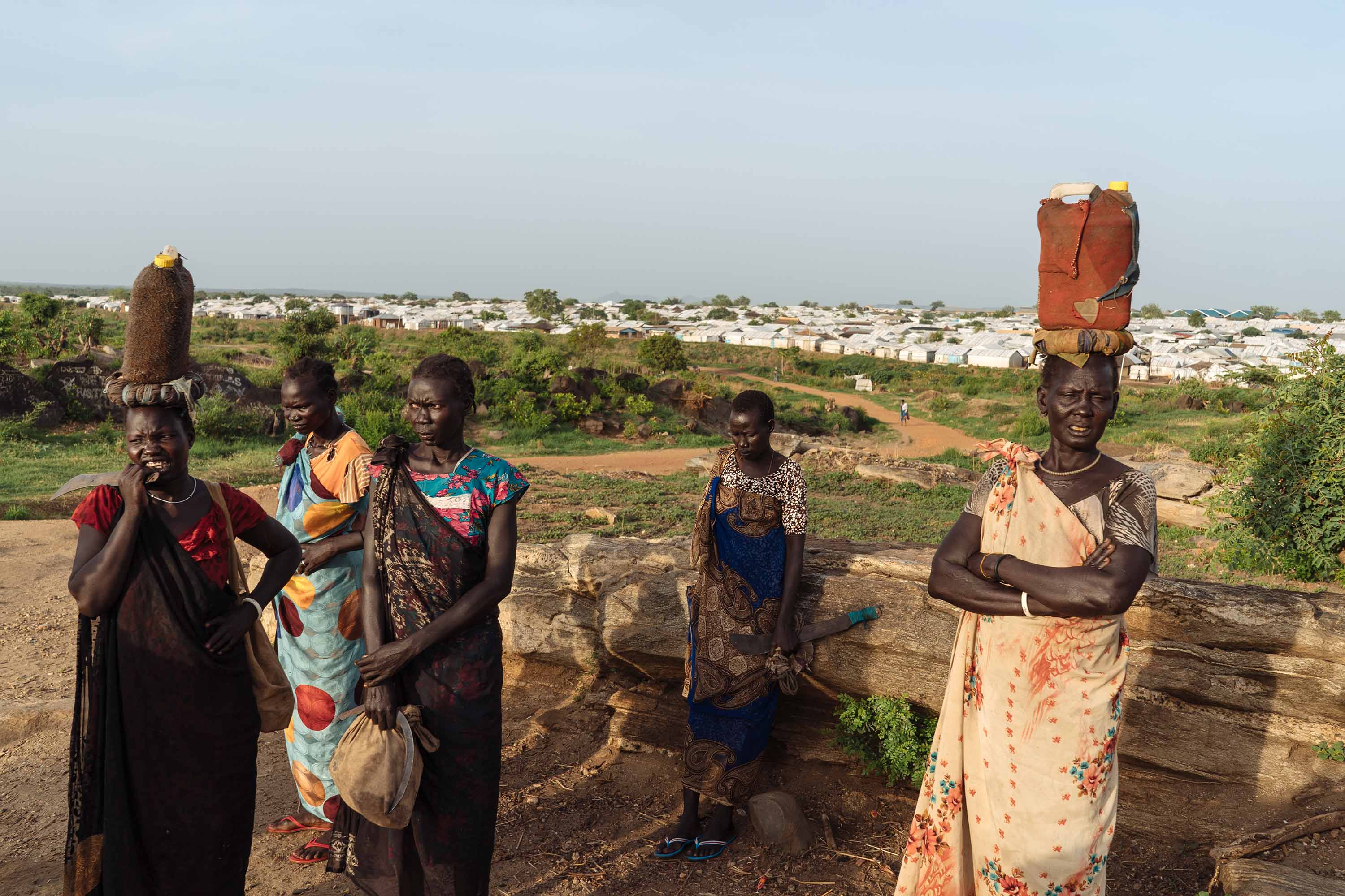 South Sudanese women wait for others to join on the way to the forest to get firewood.