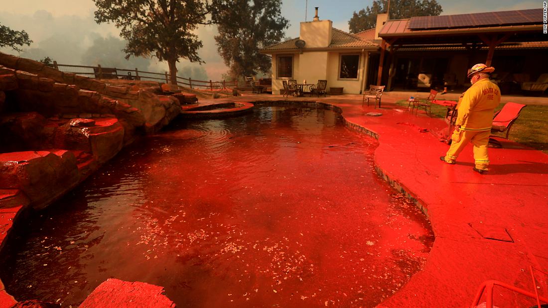 A firefighter walks around a swimming pool that had been sprayed by fire retardant near Lakeport.