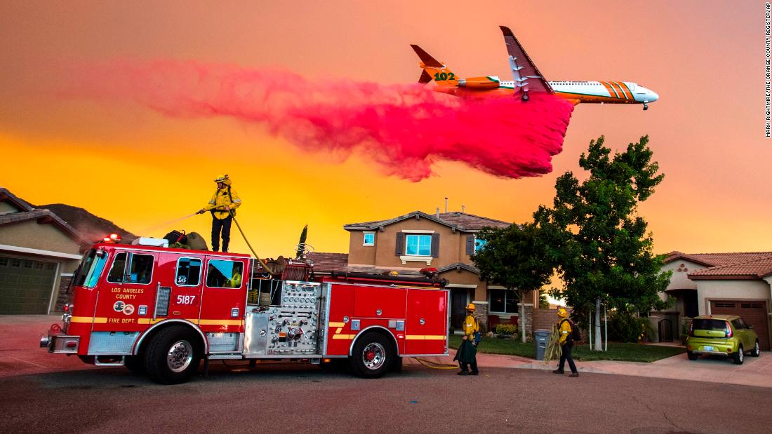 A plane drops fire retardant behind homes as the Holy Fire burns in Lake Elsinore on Wednesday, August 8.