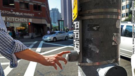 BOSTON, MA - JULY 21: A pedestrian presses a traffic signal button at Congress and Sudbury Streets in Boston on Jul. 21, 2017. The vast majority of these buttons that dot downtown neighborhoods don&#39;t actually do anything. Thats by design. Officials say the citys core is just too congested  with cars and pedestrians  to allow any one person to manipulate the cycle. (Photo by David L. Ryan/The Boston Globe via Getty Images)