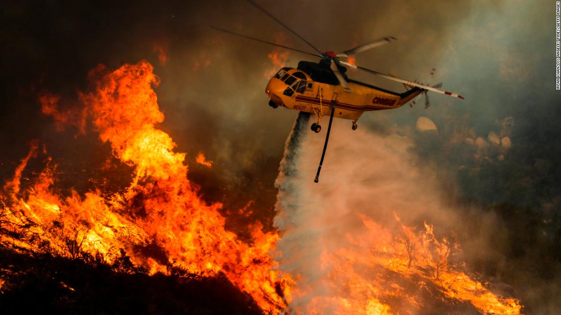 A helicopter drops water on flames in Lake Elsinore, California, on Friday, August 10.