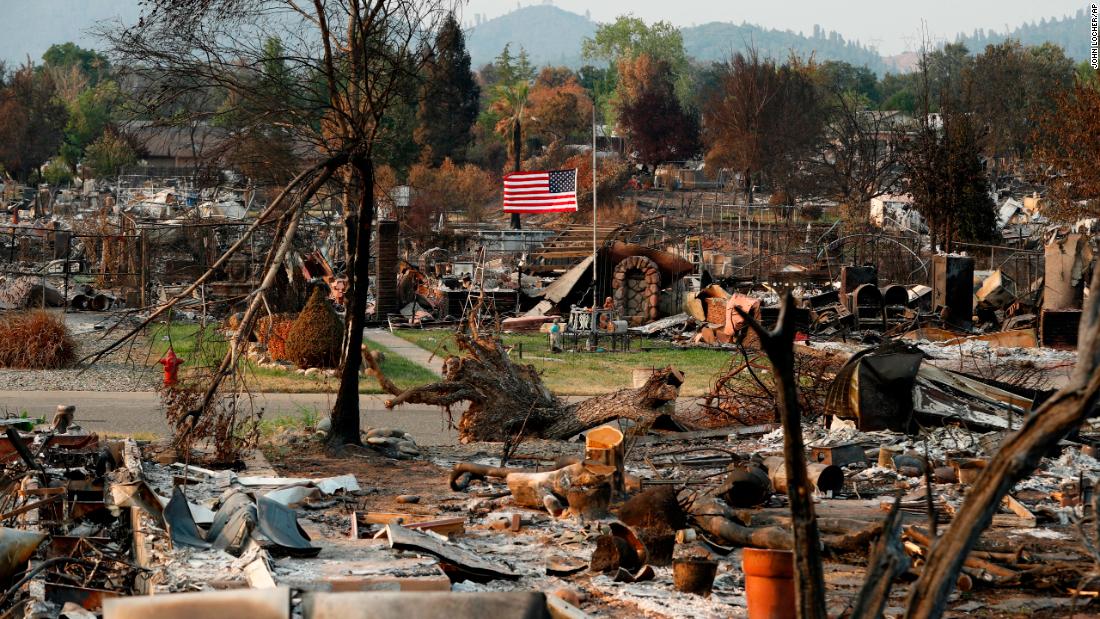 A flag flies at half-staff amid the rubble of homes burned in the Carr Fire, on Sunday, August 12.