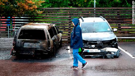 A person walks past burned cars parked at Frölunda Square in Gothenburg, Sweden, on Tuesday.