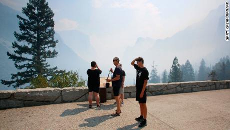 Visitors try to see through the smoke at the famous Tunnel View vista in Yosemite National Park during its reopening day. 