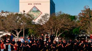 TOPSHOT - Marjory Stoneman Douglas High School staff, teachers and students return to school greeted by police and well wishers in Parkland, Florida on February 28, 2018. Students grieving for slain classmates prepared for an emotional return Wednesday to their Florida high school, where a mass shooting shocked the nation and led teen survivors to spur a growing movement to tighten America&#39;s gun laws. The community of Parkland, Florida, where residents were plunged into tragedy two weeks ago, steeled itself for the resumption of classes at Marjory Stoneman Douglas High School, where nearby flower-draped memorials and 17 white crosses pay tribute to the 14 students and three staff members who were murdered by a former student. / AFP PHOTO / RHONA WISE (Photo credit should read RHONA WISE/AFP/Getty Images)