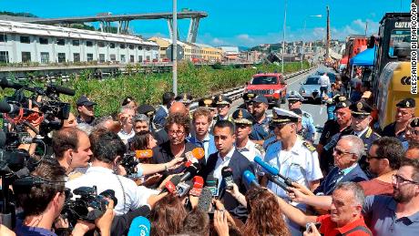 Luigi Di Maio (center right) and the transport and infrastructure minister Danilo Toninelli (center left with glasses) speak to the media in front of the collapsed bridge on Wednesday. 