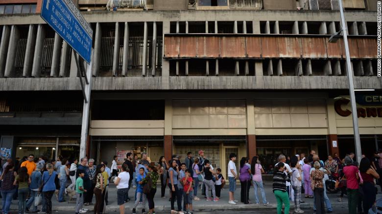 People wait in the streets after evacuating buildings in Caracas on August 21 following an earthquake.