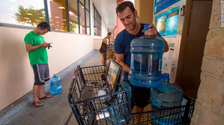 Wenkai He, left, waits to fill a 3-gallon water jug while Alex Krivoulian finishes filling three jugs at a Safeway store in Honolulu on Wednesday.