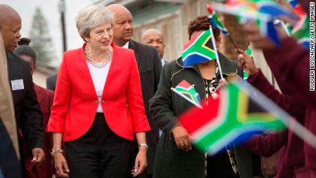 Britain's Prime Minister Theresa May (L) is greeted by schoolchildren waving British and South African flags.