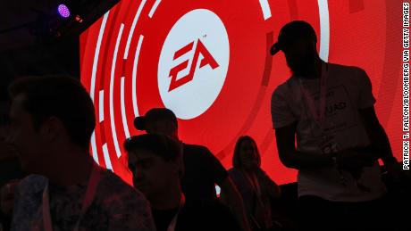 The silhouettes of attendees are seen standing in front of a Electronic Arts Inc. (EA) logo displayed on a screen during the company&#39;s EA Play event ahead of the E3 Electronic Entertainment Expo in Los Angeles, California, U.S., on Saturday, June 9, 2018. EA announced that it is introducing a higher-end version of its subscription game-playing service that will include new titles such as Battlefield V and the Madden NFL 19 football game. Photographer: Patrick T. Fallon/Bloomberg via Getty Images