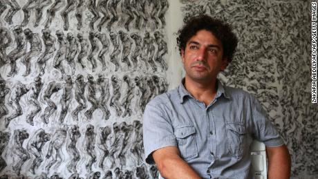 Syrian artist and painter Najah al-Bukai sits in front of his drawings which he used to document torture and the dead at Syrian prisons. 