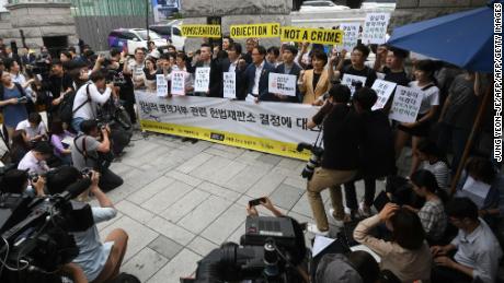 South Korean activists and conscientious objectors to military service hold yellow banners reading "Conscientious objection is not a crime" during a rally outside the Constitutional Court in Seoul on June 28, 2018.