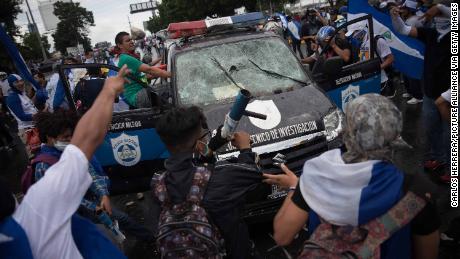 People attack a police car during a demonstration against the government in Managua on September 2, 2018.
