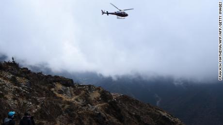 A helicopter flies over hikers headed for Everest Base Camp. Companies have been found to be billing tourists for unnecessary evacuations. 