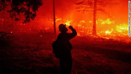 A firefighter drinks water as flames spread Thursday in Pollard Flat.