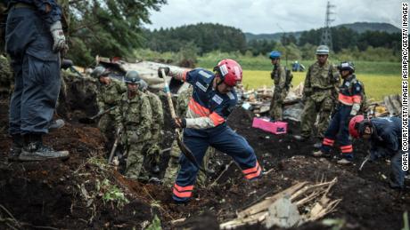 Soldiers and rescue workers search through mud covering a building in Atsuma, September 7, 2018