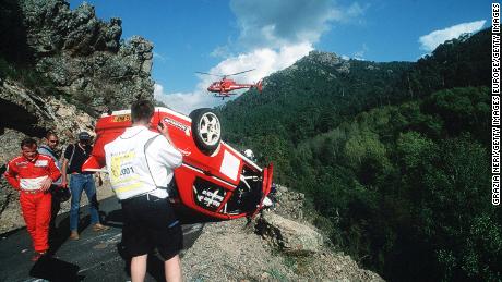 Mäkinen (left) inspects his car after a crash during Rally Corsica in 2001.