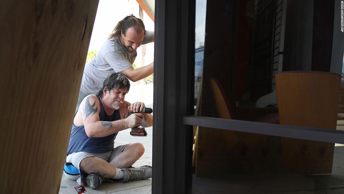 Scott Fleenor, bottom, and Jeremiah Trendell board over the windows of a business in Myrtle Beach.