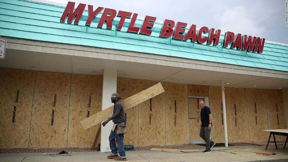 Jeff Bryant, left, and James Evans board the windows of a business in Myrtle Beach, South Carolina, on Tuesday, September 11.