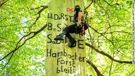 An environmental activist hangs on a rope in the Hambach Forest last month, in front of a banner with the inscription "Resistance, occupation, sabotage, Hambach Forest remains."