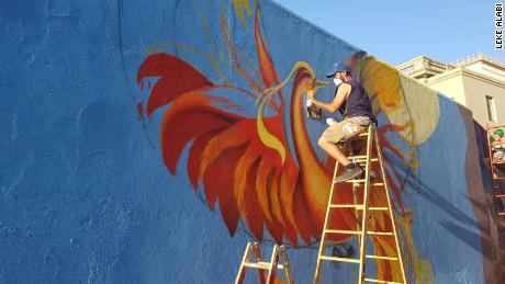 Local artist and project coordinator Dani Sánchez works on the carpet mural featuring a phoenix motif.