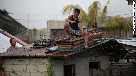 Residents secure the roof of their house as Typhoon Mangkhut approaches the city of Tuguegarao, Cagayan province, north of Manila on September 14, 2018. - Preparations were in high gear in the Philippines on September 14 with Super Typhoon Mangkhut set to make a direct hit in less than 24 hours, packing winds up to 255 kilometres per hour and drenching rains. (Photo by TED ALJIBE / AFP)        (Photo credit should read TED ALJIBE/AFP/Getty Images)