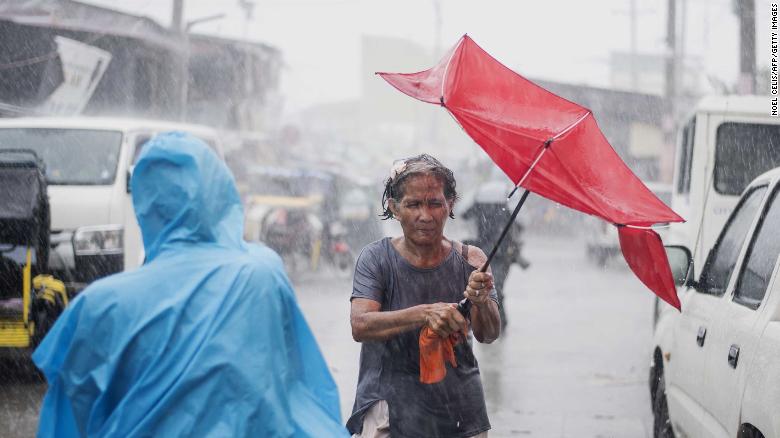 A woman in the Phillipines holds her umbrella during heavy rains caused by Typhoon Mangkhut 
