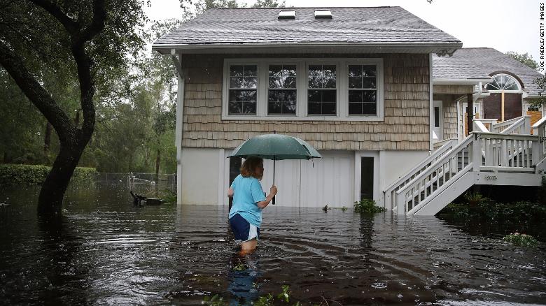 Kim Adams wades through floodwaters surrounding her home Saturday in Southport, North Carolina.