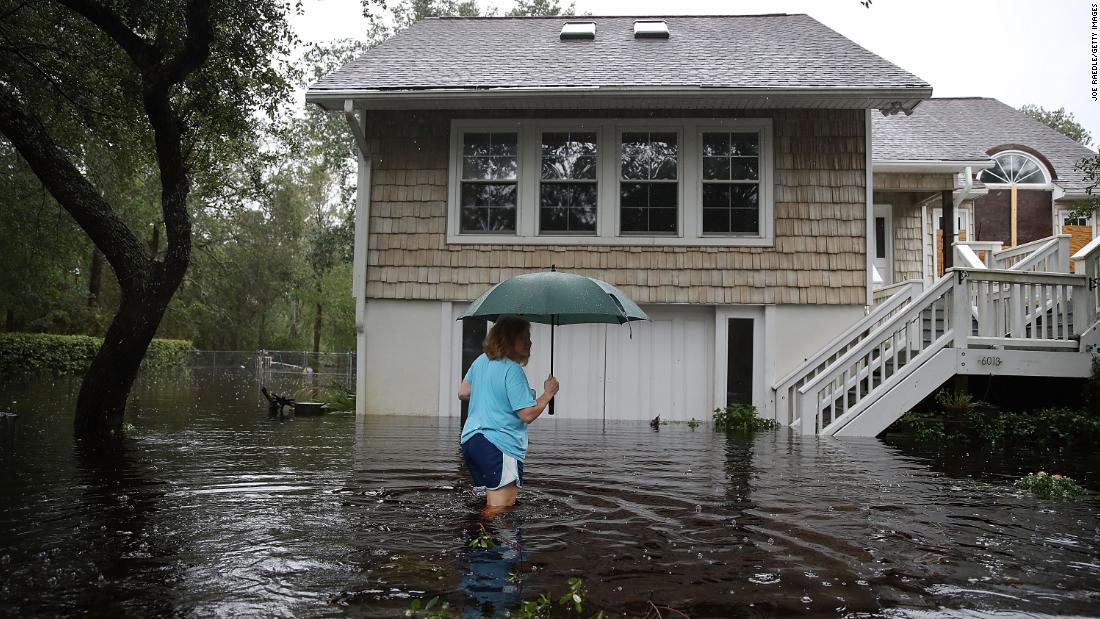 Kim Adams wades through floodwaters surrounding her home in Southport, North Carolina, on September 15.
