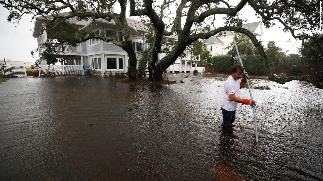 Mike Pollack searches for a drain in the yard of his flooded waterfront home in Wilmington, North Carolina, on Saturday.