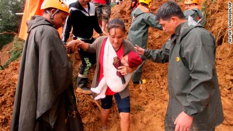 Rescuers assist a mother and her child as they evacuate to safer grounds following landslides in the Benguet province in northern Philippines on Sunday. 