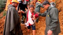Rescuers assist a mother and her child as they evacuate to safer grounds following landslides in the Benguet province in northern Philippines on Sunday. 