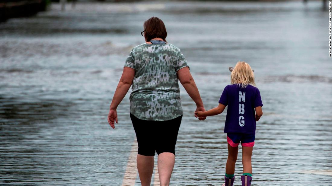 A woman and a young girl walk down a flooded road in Pollocksville on September 16.