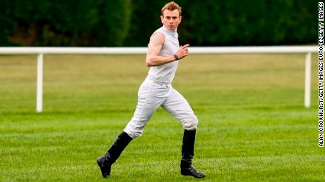 Jockey Ryan Moore races across the track after arriving from Doncaster Racecourse by helicopter.