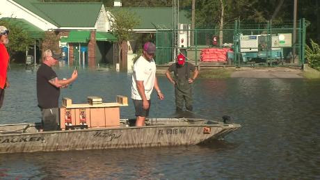 John Cassidy (black shirt, second from the left), owner of Duplicates INK in South Carolina, rides a boat with employees. The business is is in danger of flooding, but Cassidy and the employees are at work anyway. 