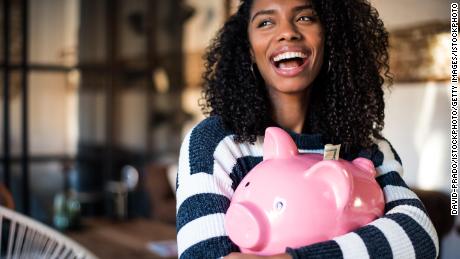 Black young woman hugging her pink piggy bank