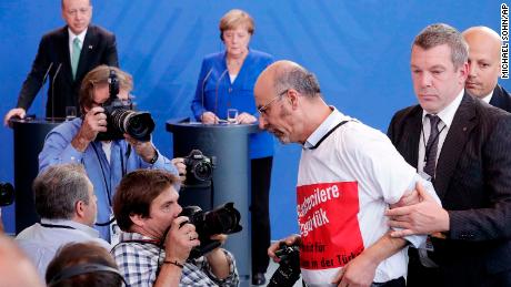 Journalist Adil Yigit is taken away as Turkish President Recep Tayyip Erdogan and German Chancellor Angela Merkel give a joint news conference in Berlin on Friday.