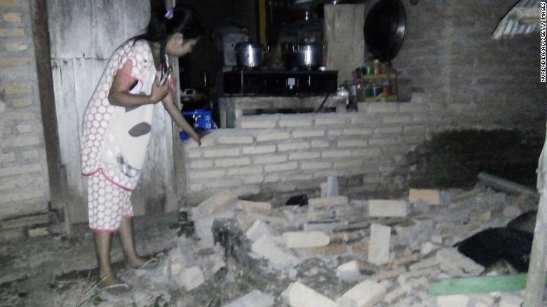 A resident is seen beside the collapsed brick wall of her house at Tobadak village in Central Mamuju, western Sulawesi province, on September 28 after a strong earthquake hit the area.