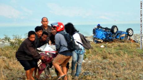 oamenii poartă o victimă în Palu pe 29 septembrie.