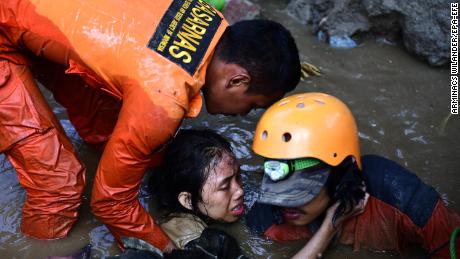 redningsmænd forsøger at befri en 15-årig jordskælvsoverlevende, der blev fanget i de oversvømmede ruiner af et kollapset hus i Palu søndag den 30.September.